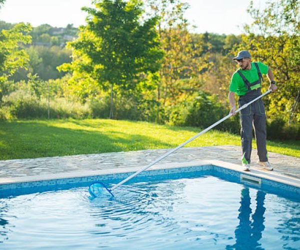 Male worker swimming pools maintainer is hired to clean out a pool in a private house.